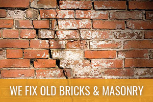 Brick wall of brown bricks that is cracked and worn