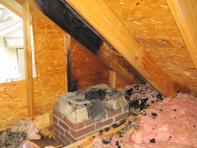Non-compliant attic repair with burnt beams and insulation.