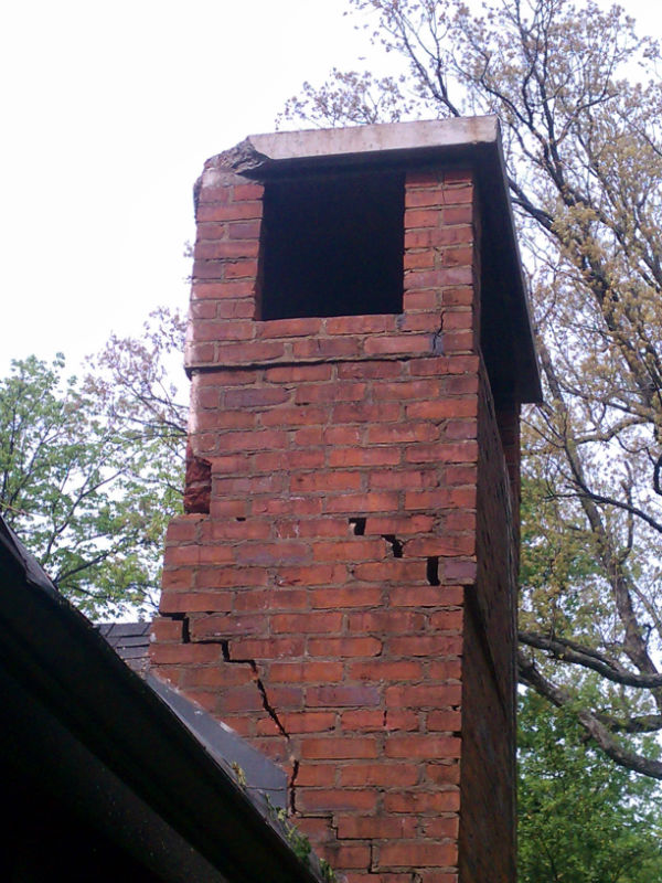 Damaged Masonry - cracks and holes - on Chimney with trees in the background