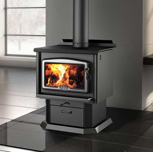 Osburn 1600 Wood Stove - Black freestanding sitting on black marble with large flames in the stove.  Windows to the left.
