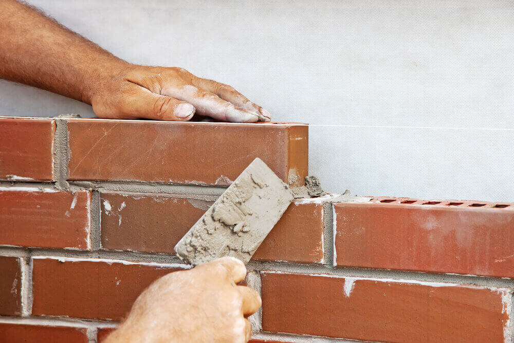 hands building a brick wall