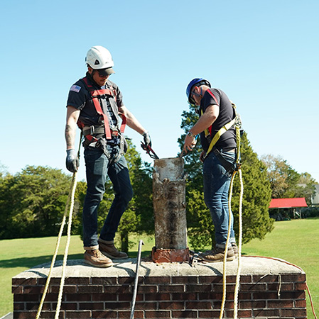 Techs wearing safety gear on top of chimney - Ashbusters Chimney