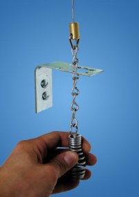 spring loaded metal top with chaining hanging attached to wall with man's hand holding it