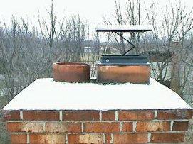 brick chimney snow covered with metal damper raised and open on top