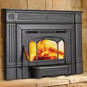 Small black wood stove insert with fire burning inside and brown brick surrounding it