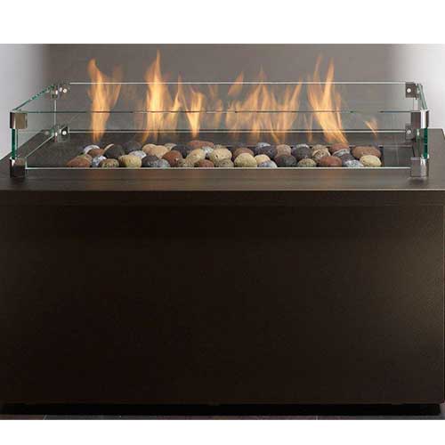 fire burning on multi colored rocks in glass fireplace enclosure