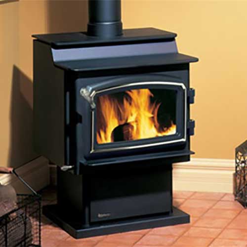 Black wood stove with fire burning in it in the corner room with red tile floor