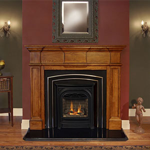 large brown hearth with red wall and mirror behind it black fireplace insert with fire burning and small stature of a man on the right