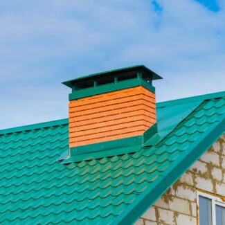 a large green chimney cap covering a masonry chimney on a green roof