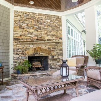a tan brick outdoor fireplace with patio furniture in front of it