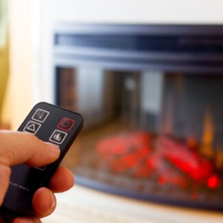 someone turning on a gas fireplace with a remote