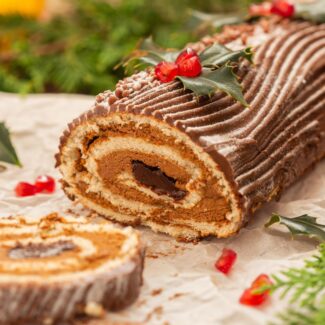 a yule log cake with christmas decor surrounding it